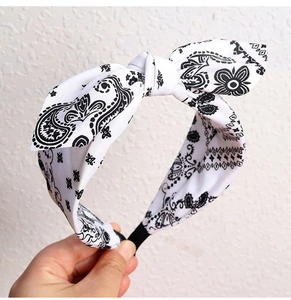 Detailed close-up of white paisley print headband featuring a top knot bow design