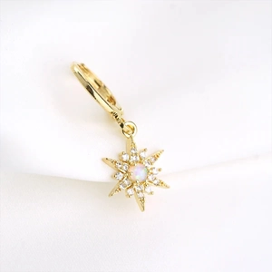 Detail of gold starburst hoop earring featuring a center opal and paved zircon stones