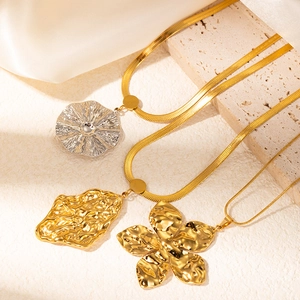 Detailed view of gold and silver irregular pleated flower pendants on snake chains