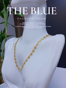 Collana a maglie a cuore dorata con motivi a stella mostrata su un manichino bianco