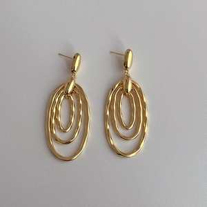 Macro detail of glossy gold layered oval drop earrings with premium metallic finish