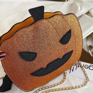 Macro shot of orange sequined pumpkin bag with black bat wings and golden metal chain