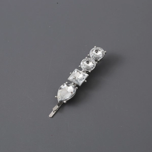 Elegant silver hair clip with multi-shape clear crystals on a minimalist grey backdrop