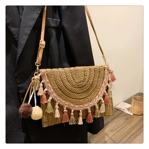 Detail of bohemian straw bag with colorful tassels, pom-poms and fine shoulder strap