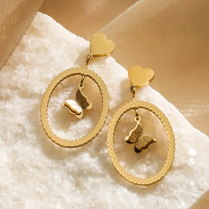 Golden butterfly drop earrings with textured oval hoops and heart studs on white stone