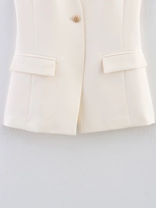 Close-up of cream halter vest with gold woven button and functional flap pockets