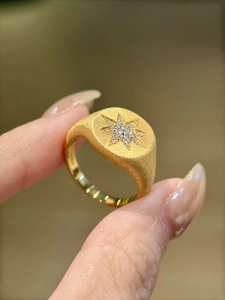 Detailed macro of gold-plated starburst ring with crystal inlay and brushed texture