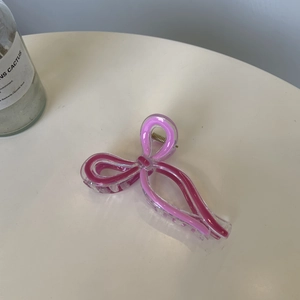 Detail of pink ribbon bow hair claw clip made of acrylic with gold metal spring