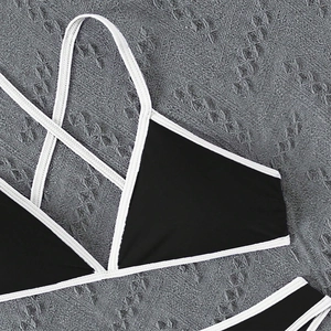 Detail of black bikini top with white contrast piping and adjustable criss-cross straps