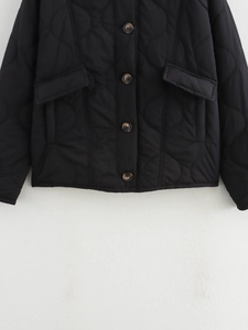 Detailed view of black quilted jacket featuring dark brown buttons and large flap pockets