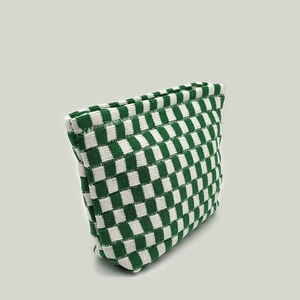 Detailed close-up of large knit checkered makeup bag with green and white grid pattern