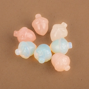 Macro detail of translucent pine cone beads in pastel pink and blue on brown background