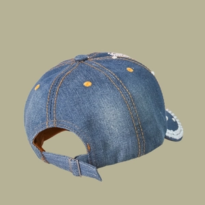 Detail view of blue denim baseball cap back with metal buckle and yellow stitching