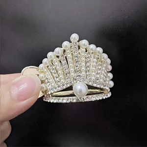 Macro view of golden crown hair claw clip with inlaid pearls and sparkling rhinestones