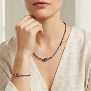 Detail of blue sodalite beaded necklace and bracelet set with gold accents on model