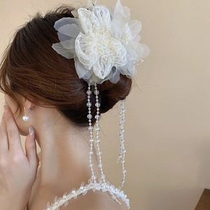 Detail einer Organza-Blumen-Haarklammer mit eleganten langen Perlenquasten am Modell