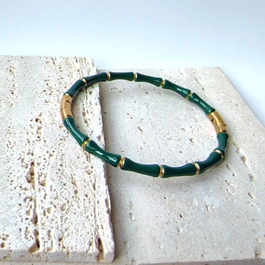 Detail shot of a bamboo-style bracelet featuring green enamel and 18k gold plating