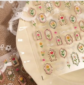 Detail of vintage flower nail stickers with gold metallic frames on ceramic tray