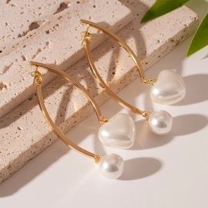 Detail of vintage gold curved earrings featuring heart and round resin pearls on stone