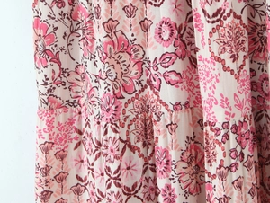 Close-up of pink floral chiffon fabric showing bohemian patterns and layered pleats
