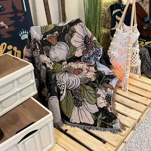 Detail of woven floral camping blanket with tassels and large botanical patterns
