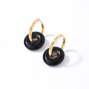 Détail de boucles d'oreilles créoles dorées en acier avec pendentifs pierre noire