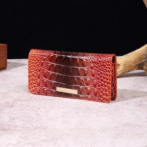 Macro shot of crocodile embossed texture and brushed gold hardware on brown wallet