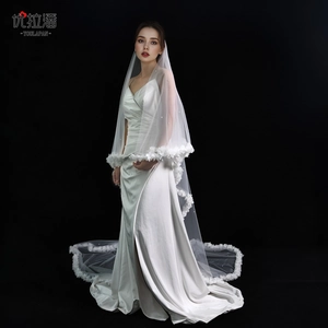 Detail of long white bridal veil featuring delicate 3D floral lace edges on satin fabric