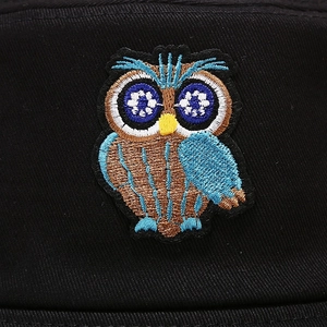 Macro detail of vibrant owl embroidery on premium black cotton twill bucket hat