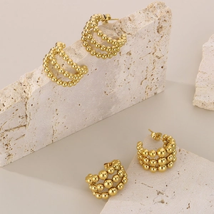 Close-up of golden multi-layer beaded hoop earrings on light stone texture