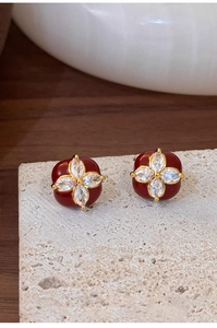 Close-up of gold-plated square flower earrings with red enamel and sparkling zircons