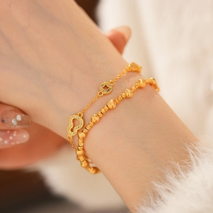 Detailed close-up of a 24k gold plated double-layer bracelet with gourd and coin charms