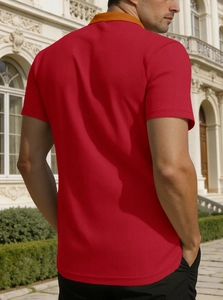 Gros plan du polo rouge à manches courtes avec col orange et tissu en maille texturé