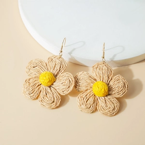 Detail of handmade raffia flower earrings with yellow petals and gold hooks