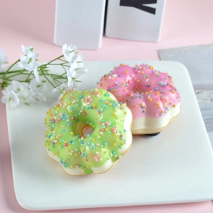 Realistic PU squishy donut models in pink and green on a white plate background