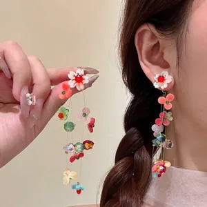 Detail of floral butterfly tassel earrings with colorful beads and white petals on model