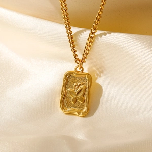 Macro view of vintage 18K gold plated square coin pendant featuring butterfly relief