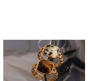 Close-up of gold chain style rings with square spotted marble and tiger eye stones