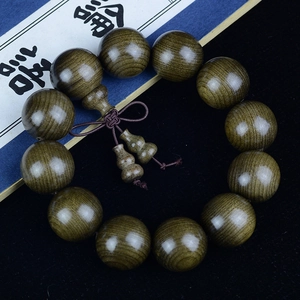 Macro detail of aged ebony wood prayer beads with clear grain and gourd pendants