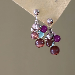 Close-up of cat-eye stone tassel earrings with colorful beads and silver hooks