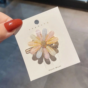 Macro shot of colorful gradient resin flower hair clips with rhinestones on gold pins