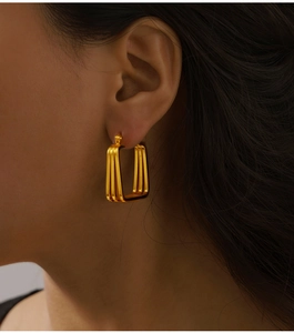 Macro view of gold multilayer geometric rectangle earrings on a female model