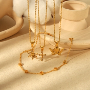 Gold-plated floral and cross jewelry set with necklace and bracelet on beige background