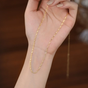 Polished 18K gold water wave chain necklace shown on hand with adjustable clasp
