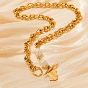Elegant gold chain necklace with baroque pearl and engraved square pendant on silk background