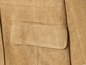 Close-up of faux suede fabric texture and stitching on a camel blazer flap pocket