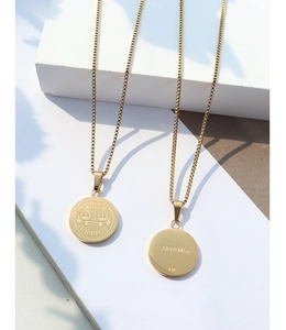 Macro view of gold necklaces with Justice scales pendant and 14K engraving