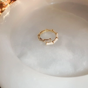 Close-up of golden bamboo ring with white enamel and sparkling zircon pavé details