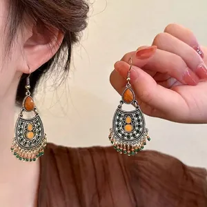 Close-up of Bohemian earrings with bronze openwork and colorful beads in retro style