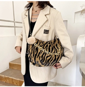 Detail of plush tiger print tote bag with thick gold chain strap and fuzzy pompom charm